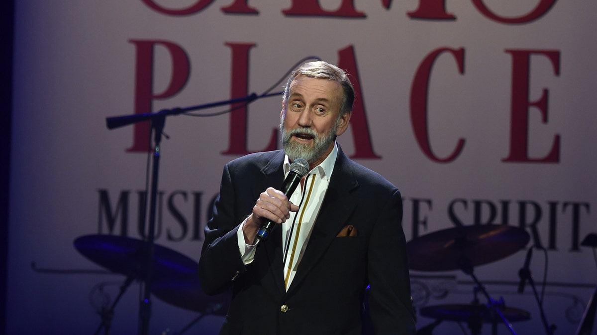 Ray Stevens holds a mic on stage