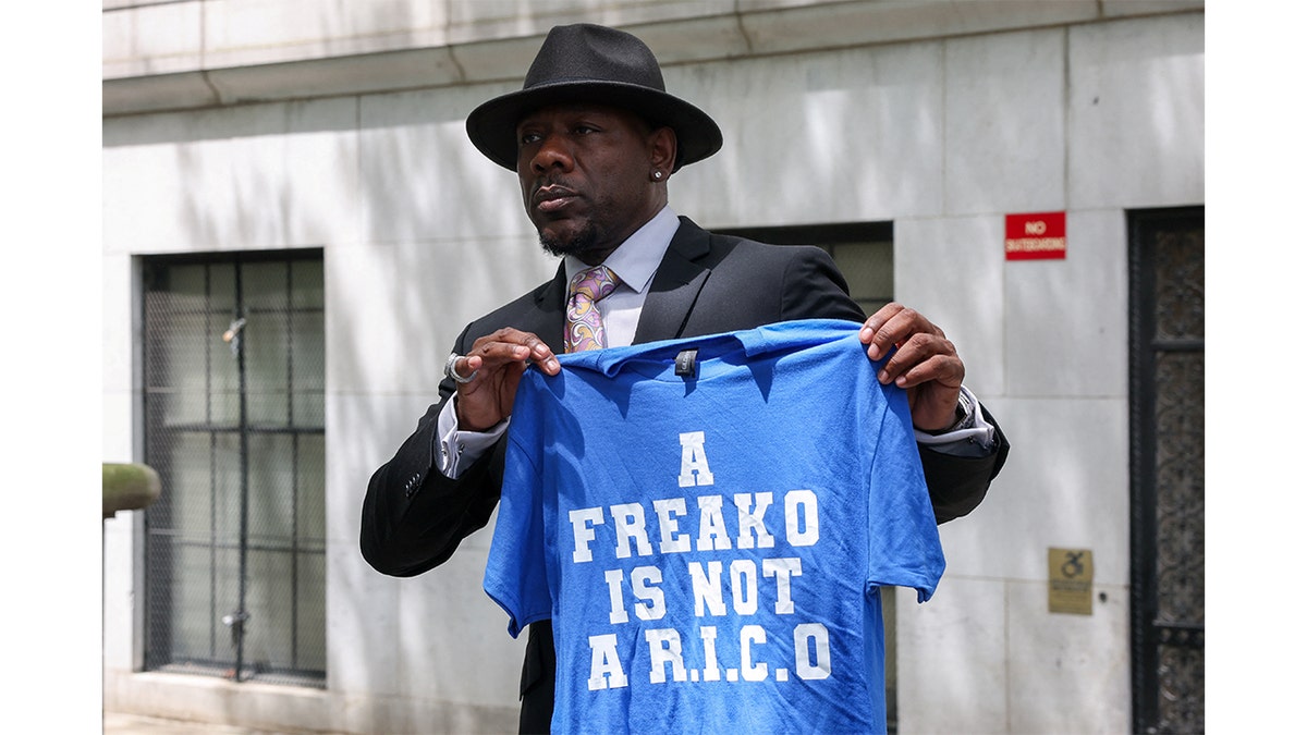 A man holds up a shirt while supporting Diddy at his trial