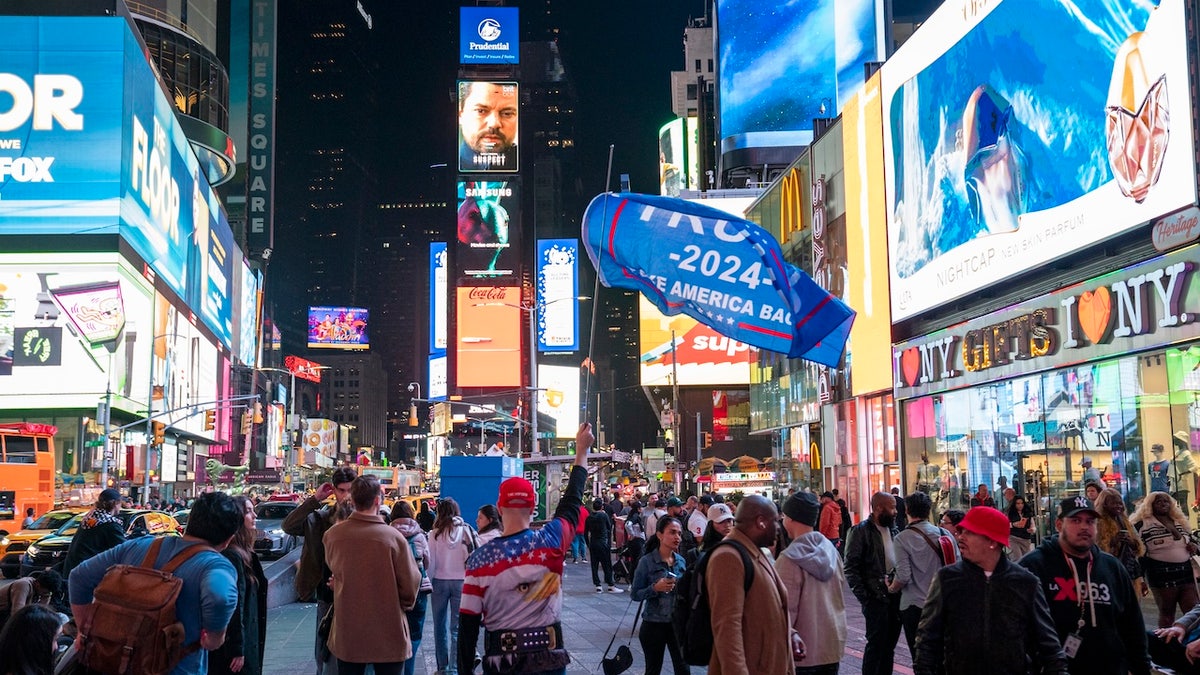A pro-Trump supporter holds a banner in Times Square on November 5, 2024 in New York City. Americans cast their ballots today in the presidential race between Republican nominee former President Donald Trump and Democratic nominee Vice President Kamala Harris, as well as multiple state elections that will determine the balance of power in Congress. (Photo by Robert Nickelsberg/Getty Images)
