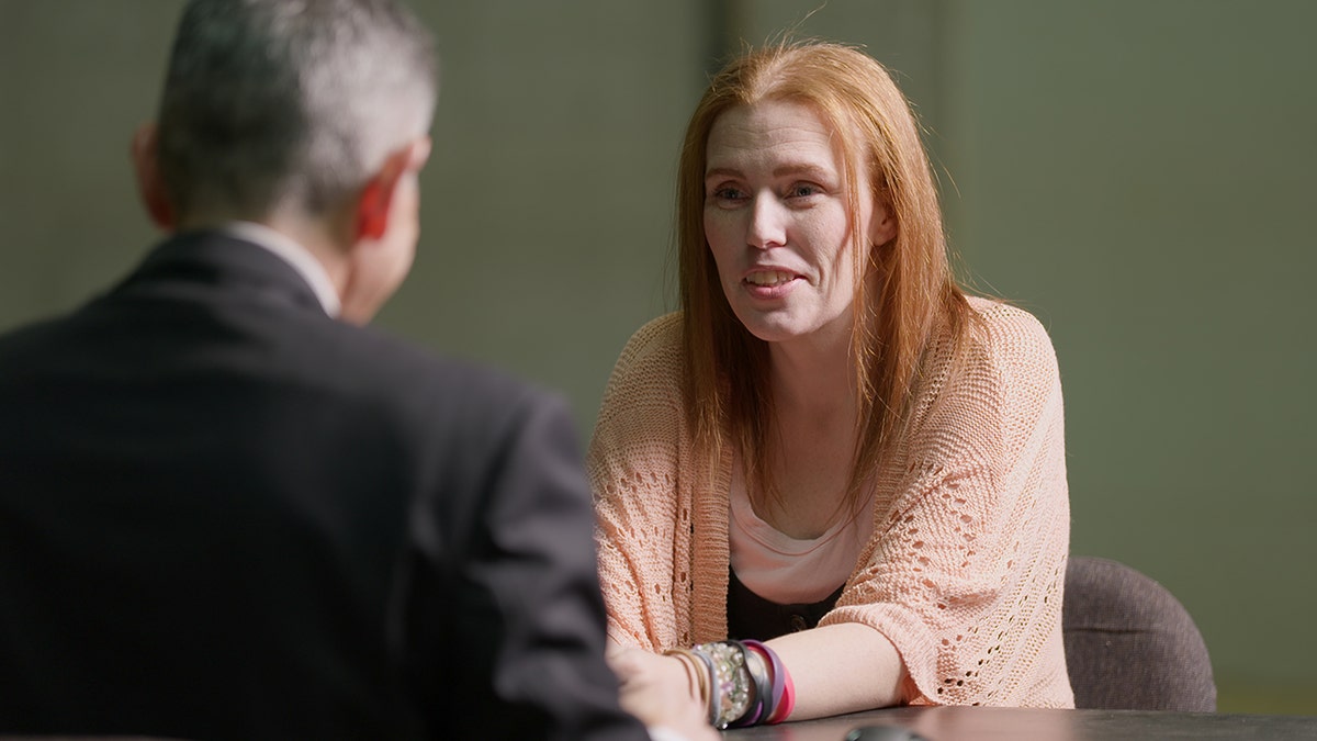 Shannon Price wearing an orange shawl being interviewed by George Olivo.