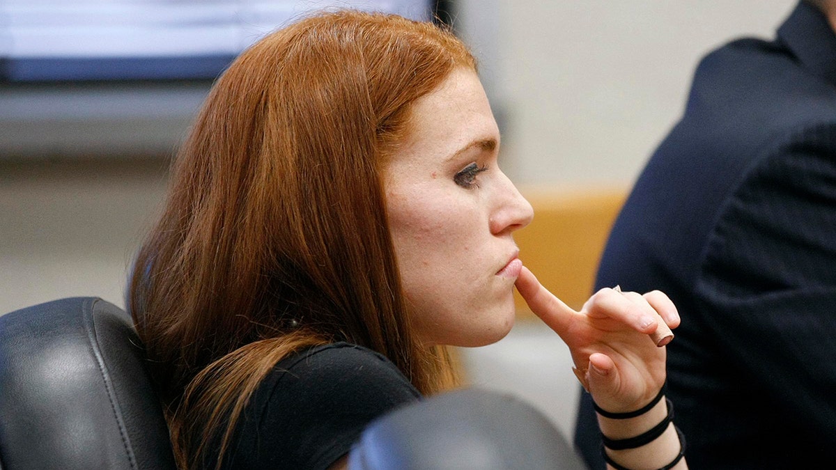 Shannon Price looking ahead with her finger placed on her lip.