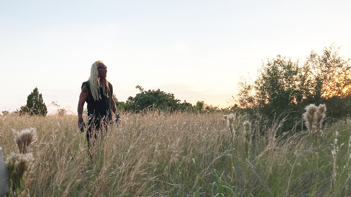 Dog the Bounty Hunter in a grassy field as the sun goes down