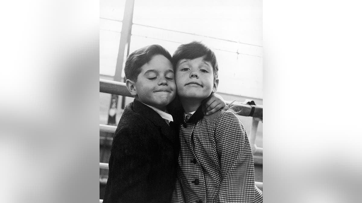 Lucille Ball and Desi Arnaz's children holding each other and smiling.