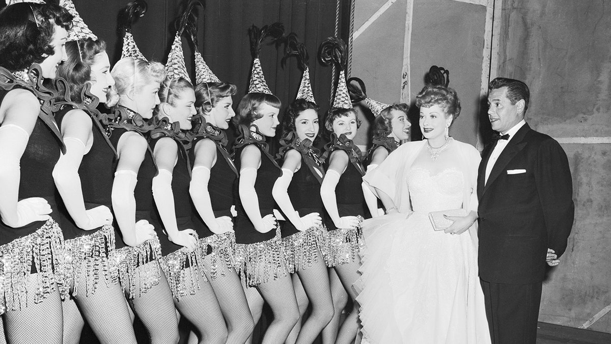 Desi Arnaz staring at a group of showgirls next to Lucille Ball.