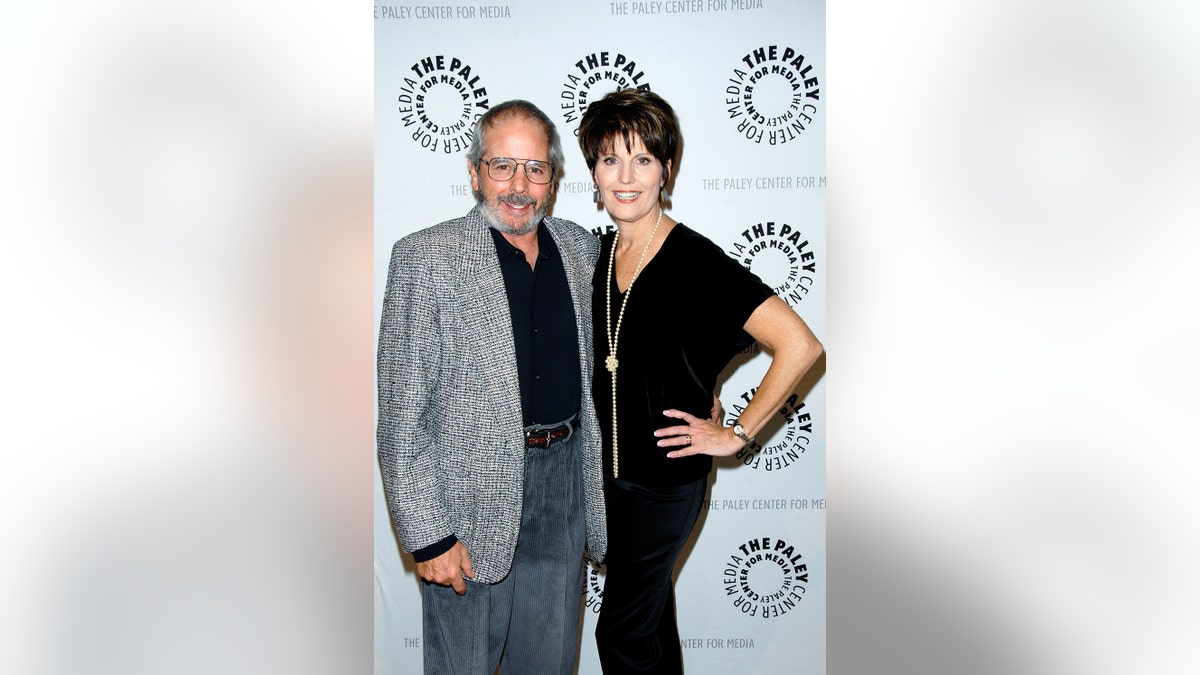 Desi Arnaz Jr. and Lucie Arnaz leaning in close to each other and smiling in casual wear.
