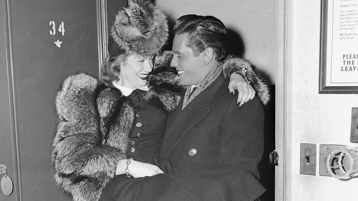 Desi Arnaz carrying Lucille Ball wearing a fur coat and a matching hat.