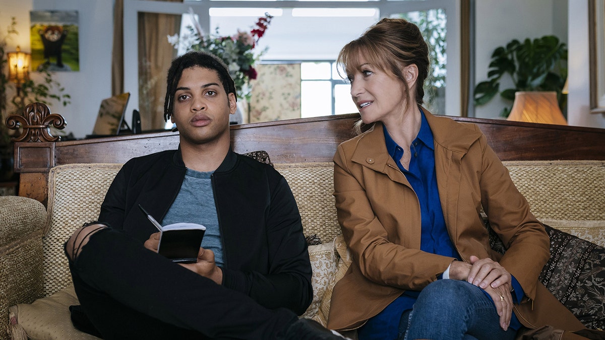Jane Seymour chatting with Rohan Nedd on a couch from a scene in "Harry Wild."
