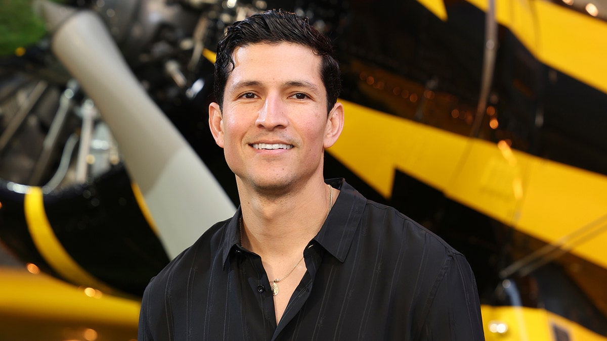 Danny Ramirez wears black button down shirt.