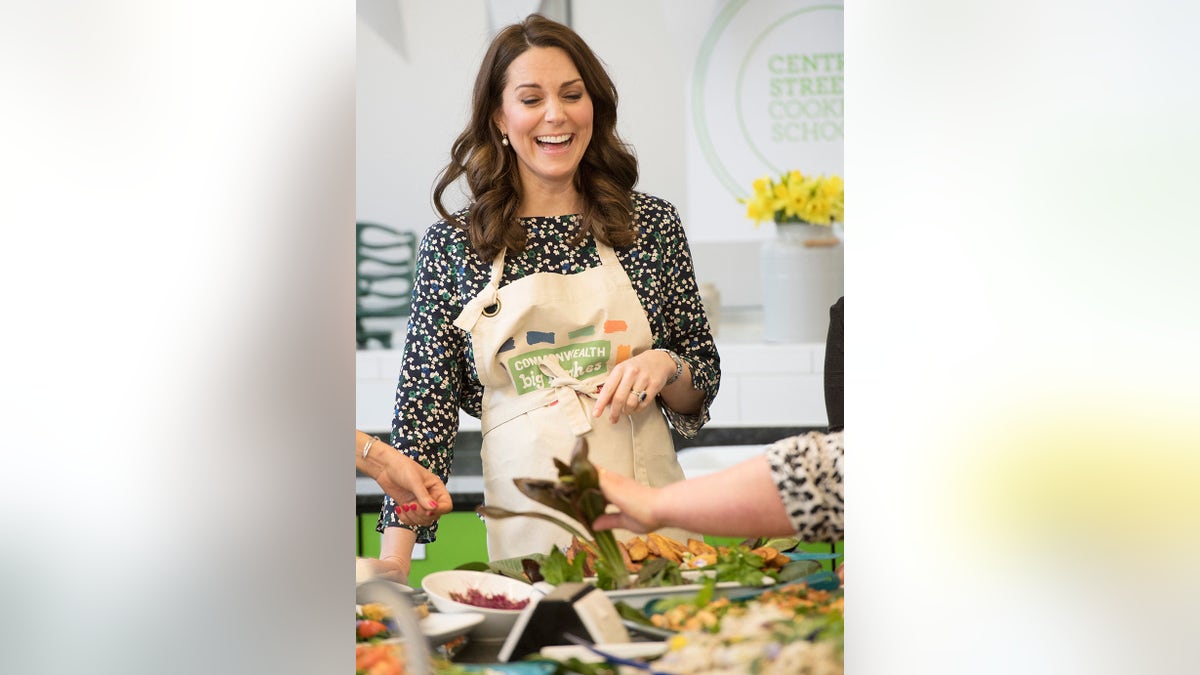 Kate Middleton in a polka dot dress with an apron laughing.