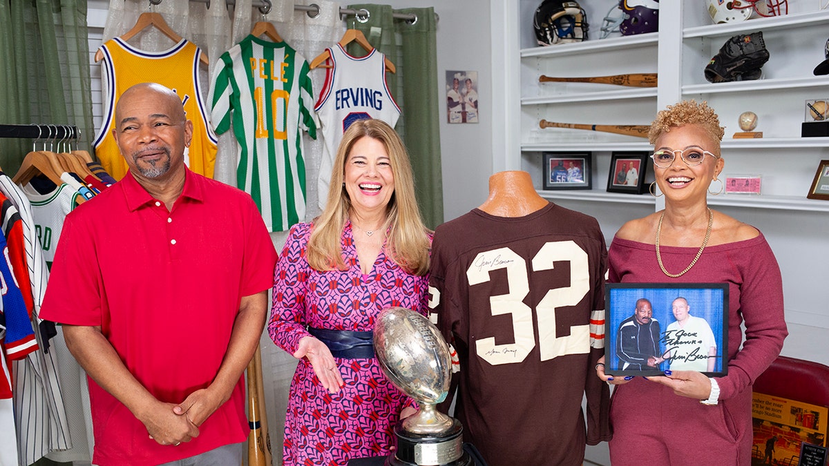 Lisa Whelchel smiling wearing a bright pink collection posing with a sports collection.
