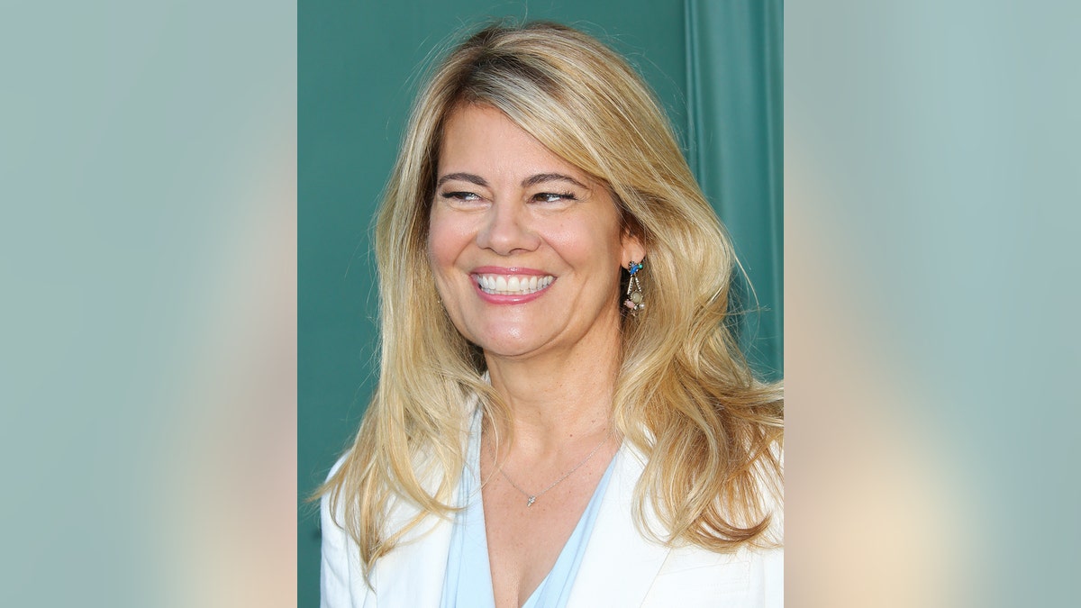 An up-close of Lisa Whelchel smiling wearing white.