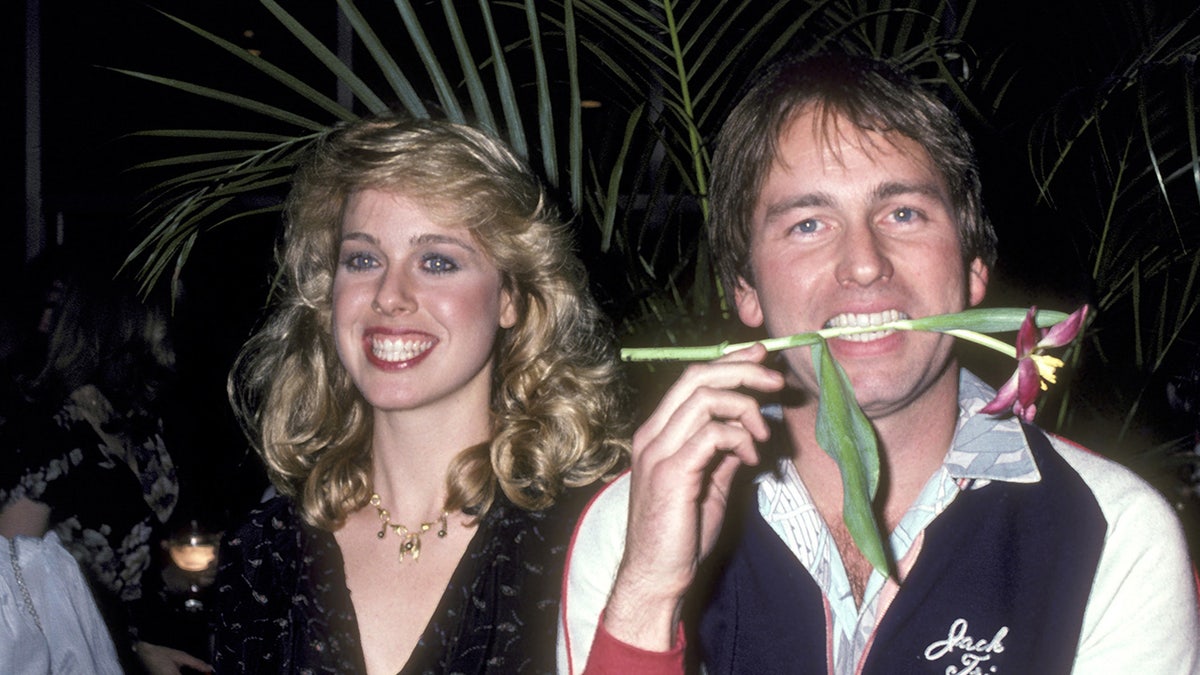 Jenilee Harrison smiling next to John Ritter with a flower between his teeth.