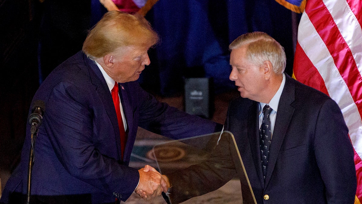 Then-former President Donald Trump and Sen. Lindsey Graham shake hands in 2023