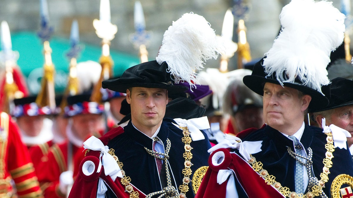 Prince William and Prince Andrew walking in royal robes looking serious.