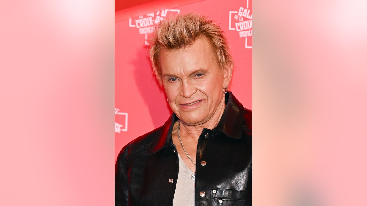A close-up of Billy Idol wearing a black jacket and a white shirt.
