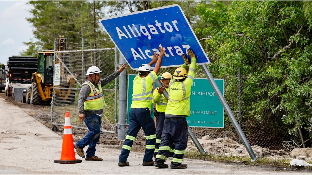 Workers install a sign for a new Florida migrant detention center