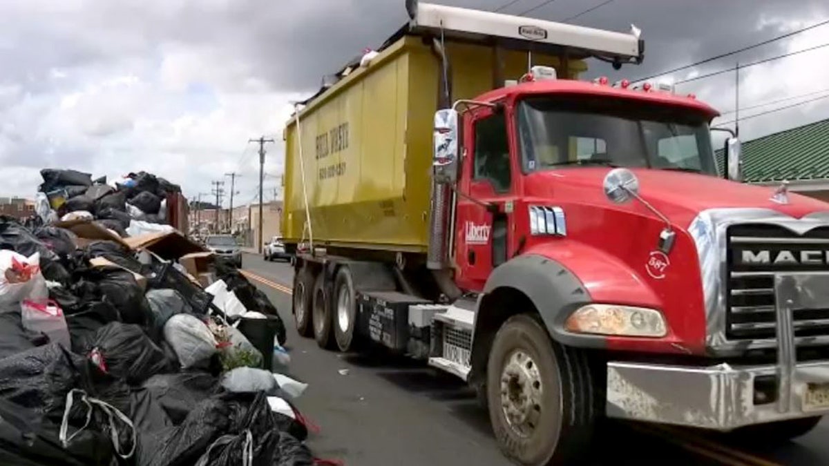 A truck driving past piles of trash in the street