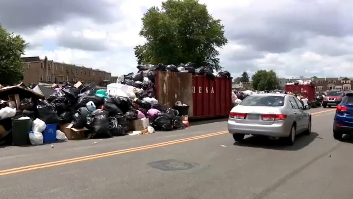 car driving by piles of trash lining the street