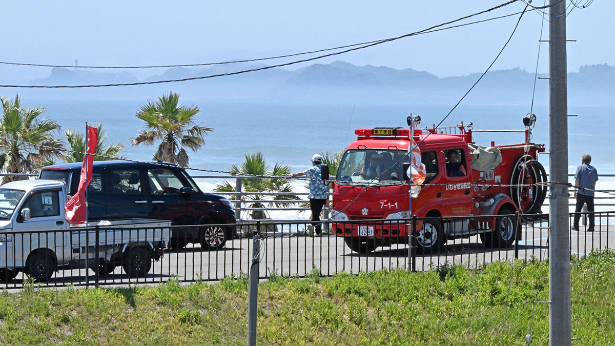 People watch the coast area from higher ground after Japan issued evacuation alert