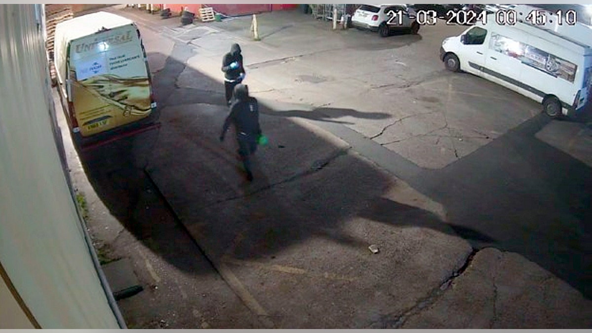 Suveillance footage of two hooded men in a parking