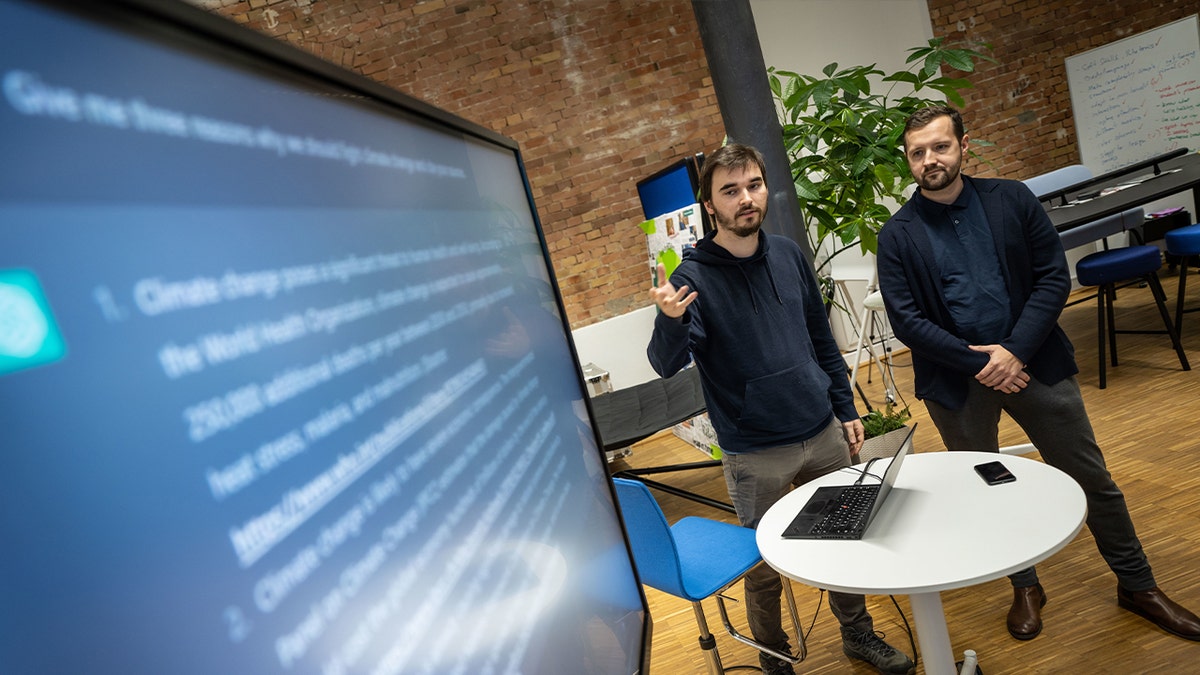 two men presenting at large screen in office