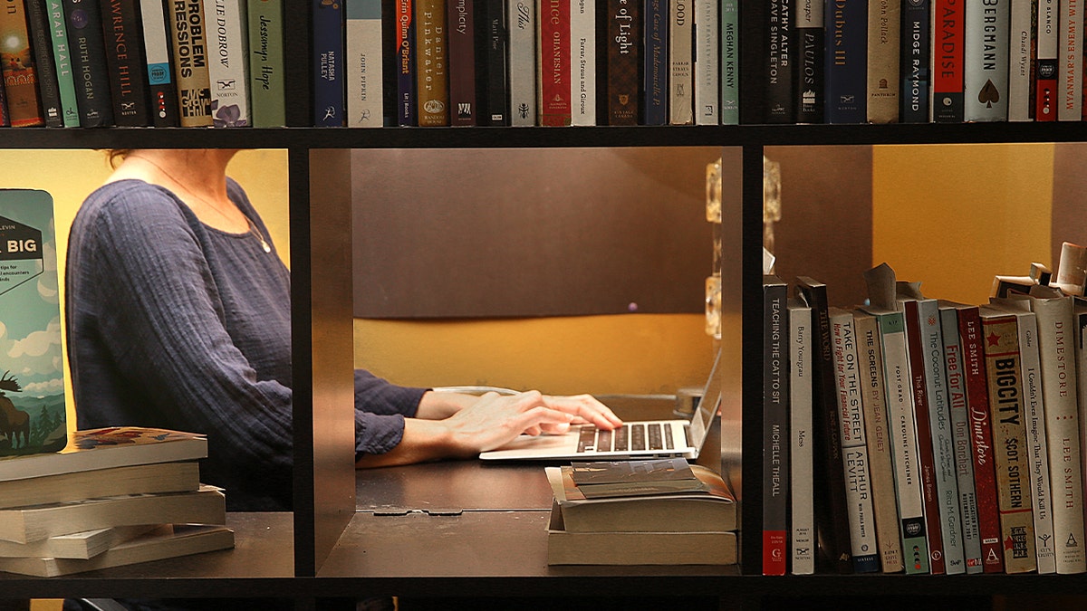 woman writing behind bookcase