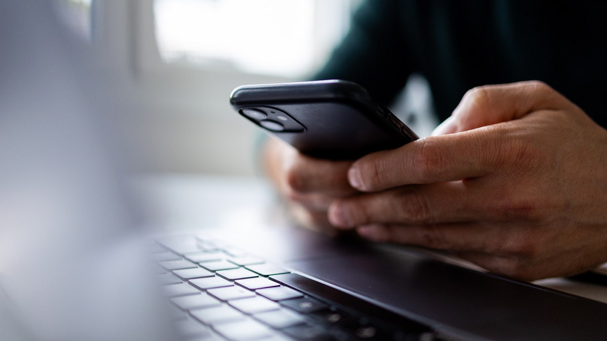 Hands typing on smartphone