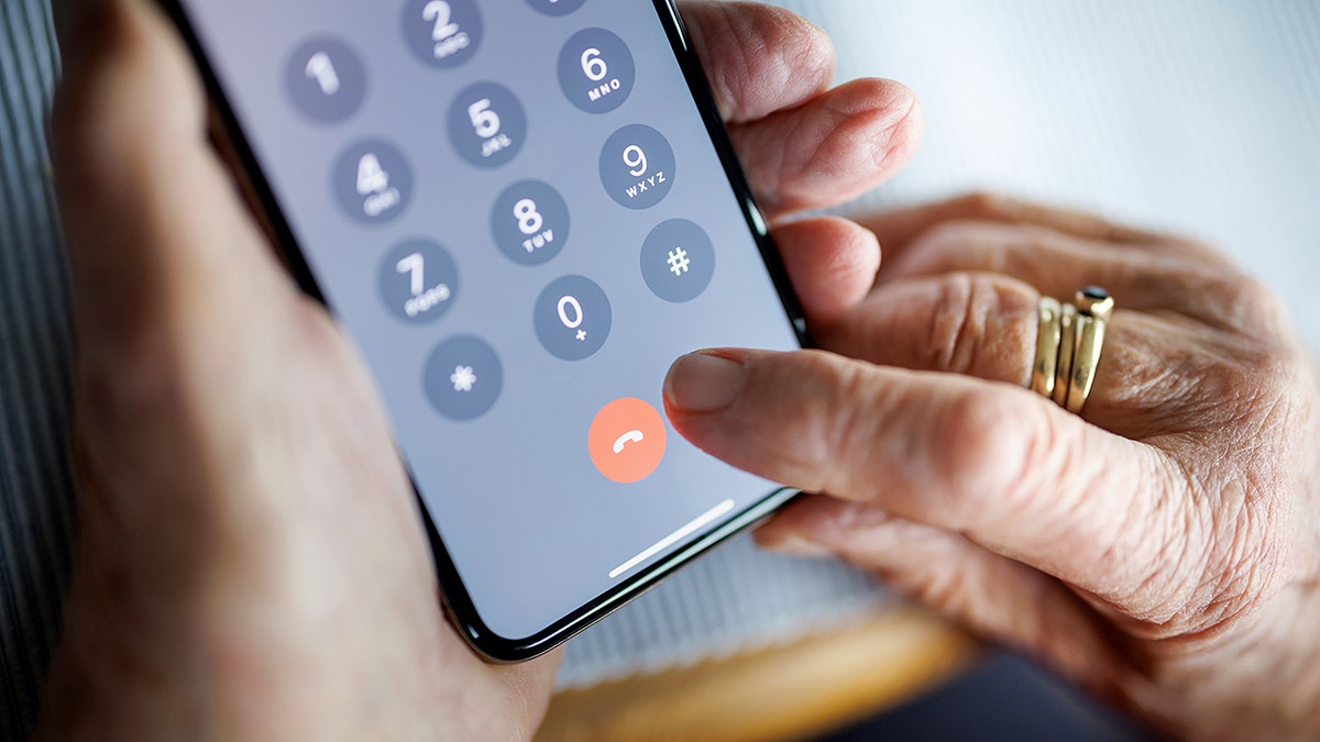 An elderly person hanging up a phone