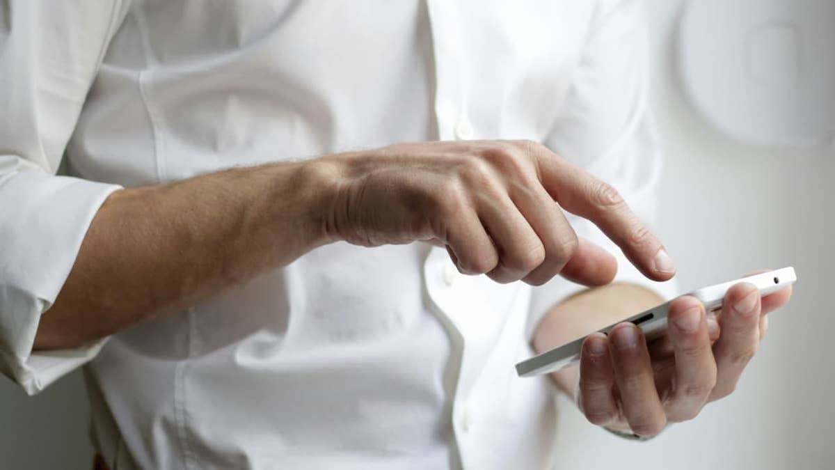 A man uses a smartphone, illustrating the vulnerability of mobile devices in modern cybercrime.