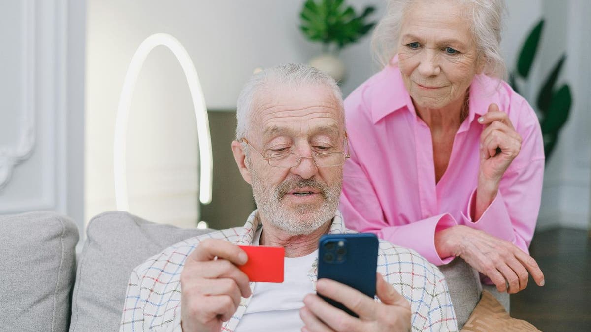 An elderly man purchasing something with his credit card online