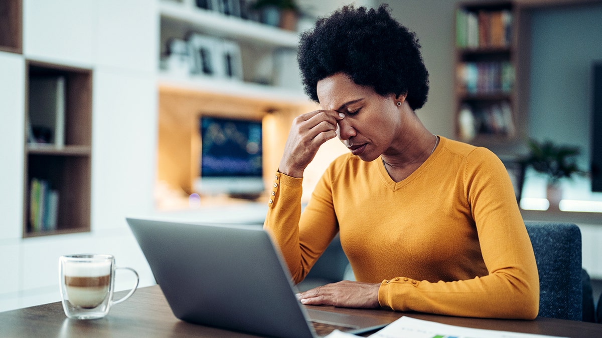 Woman holds her face after looking at her computer