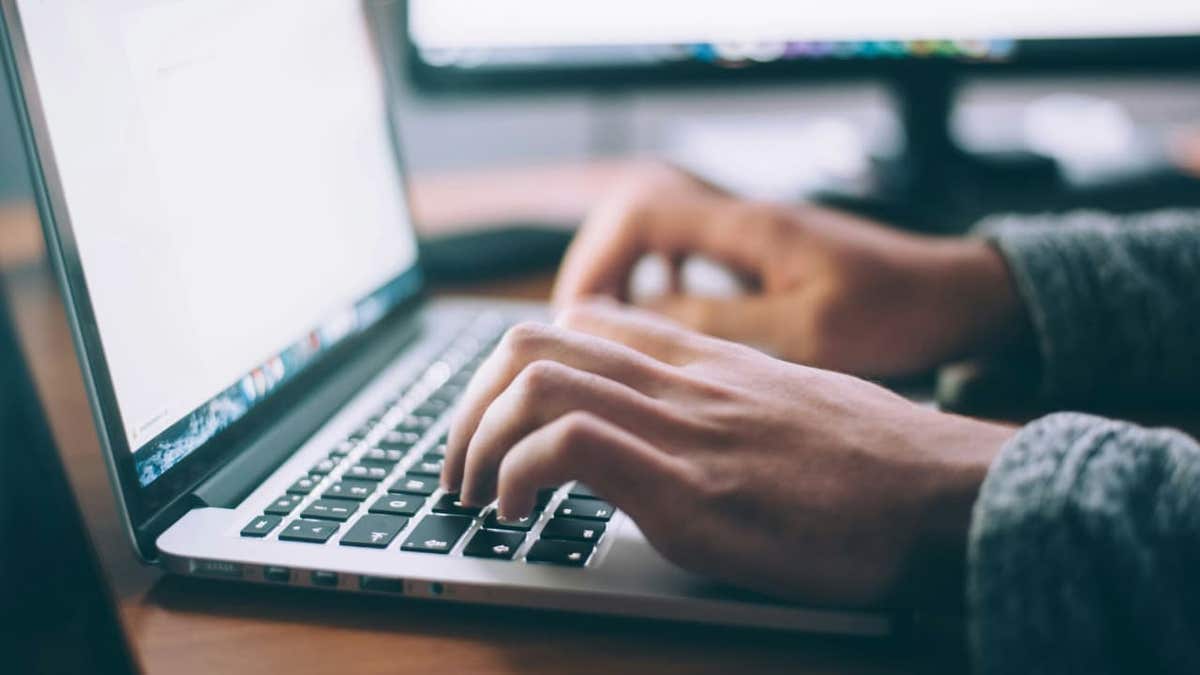 A person types on a laptop computer in a home office setting, representing remote access points targeted in data breaches.