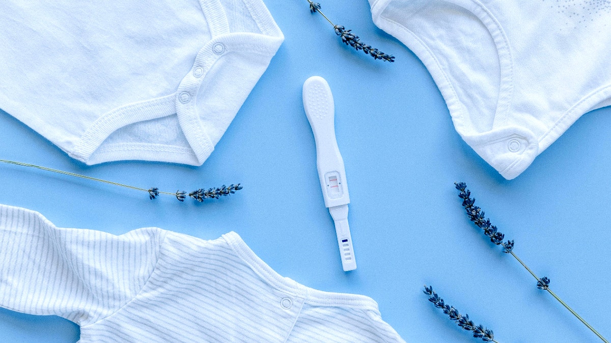 Baby onesies around a pregnancy test