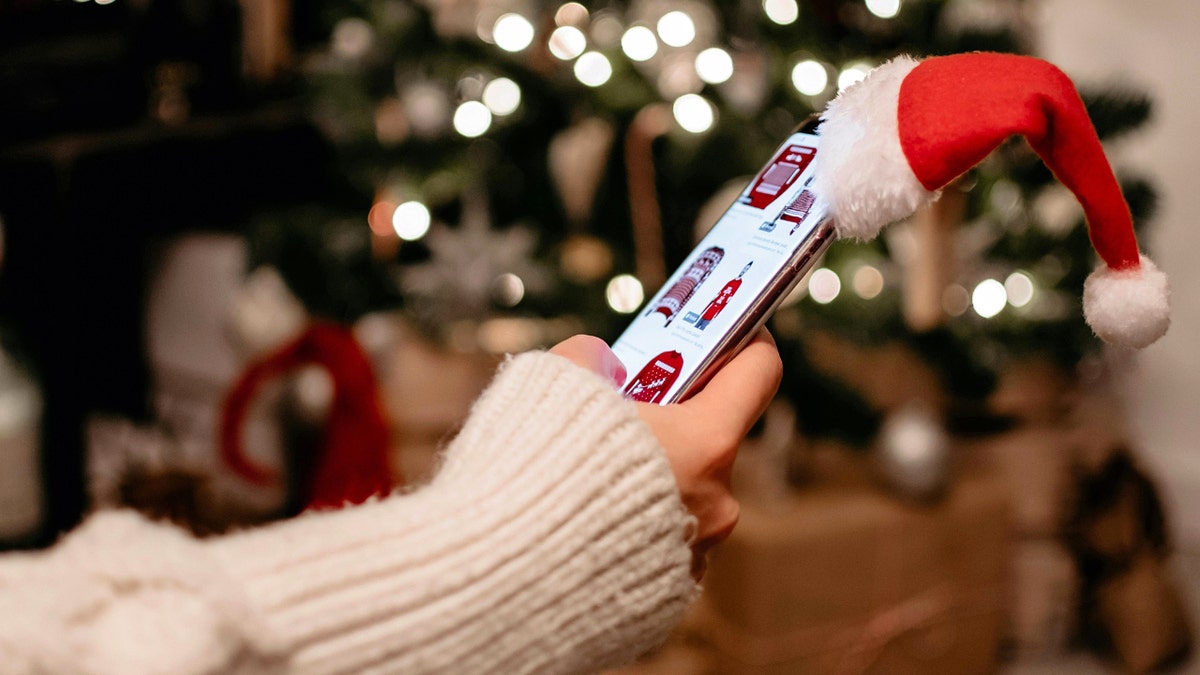 A person holding a phone with a Santa hat on it