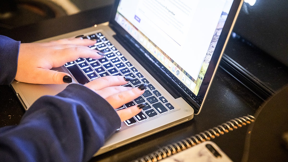 Teen typing on their laptop.
