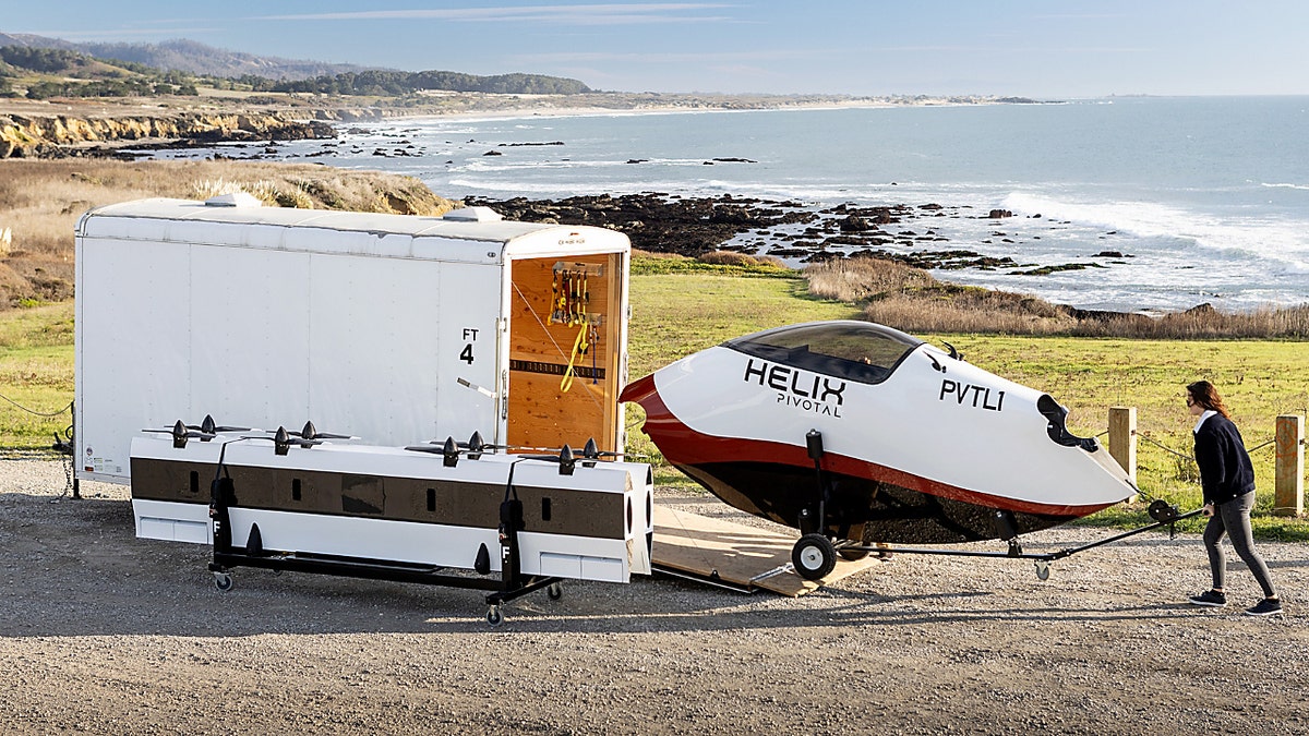 Pivotal flying car being put in a unit near the beach by a woman.