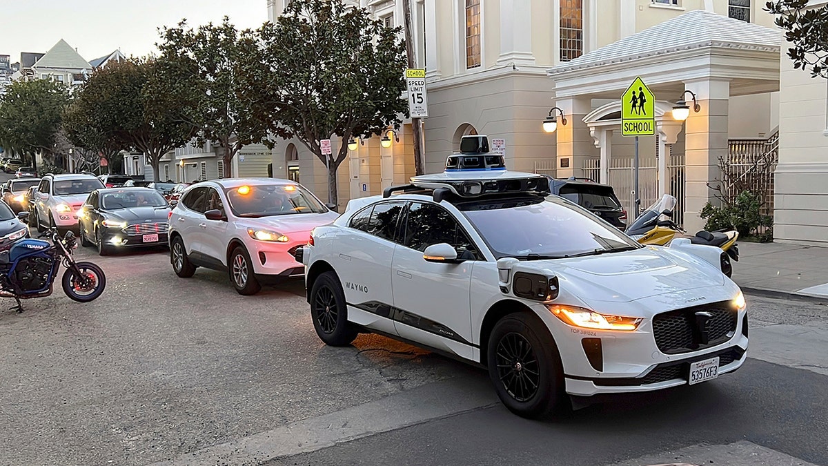 A Waymo taxi parked in front of a line of cars