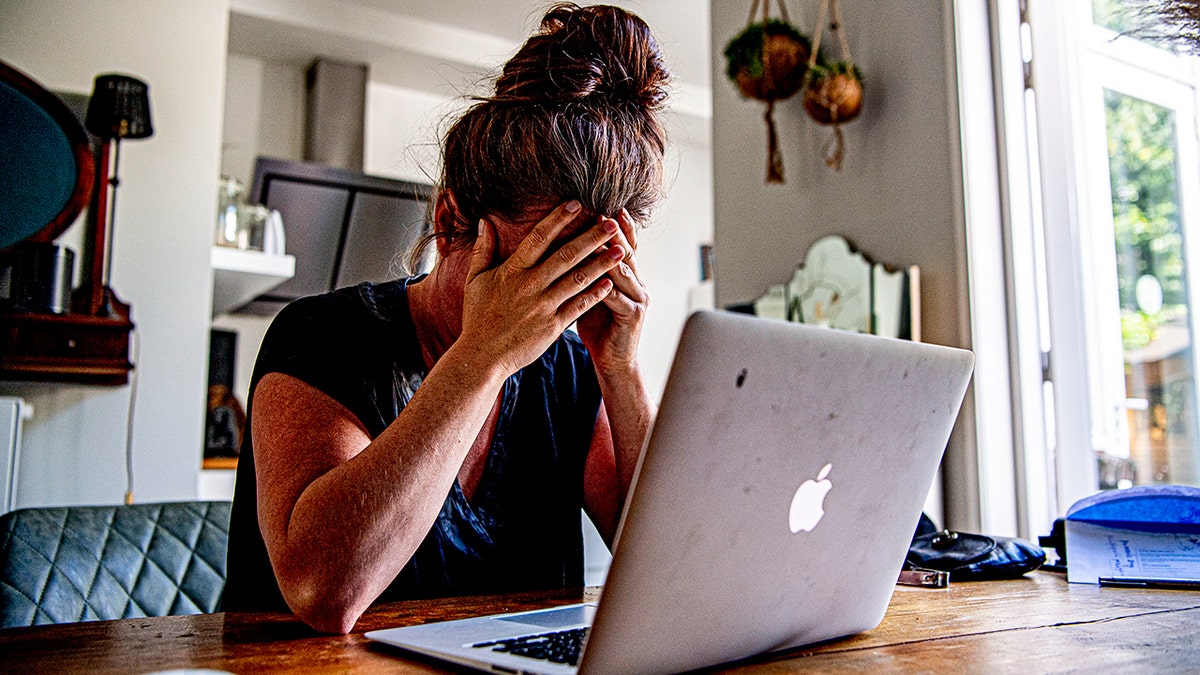 Woman appearing to be stressed at her computer.