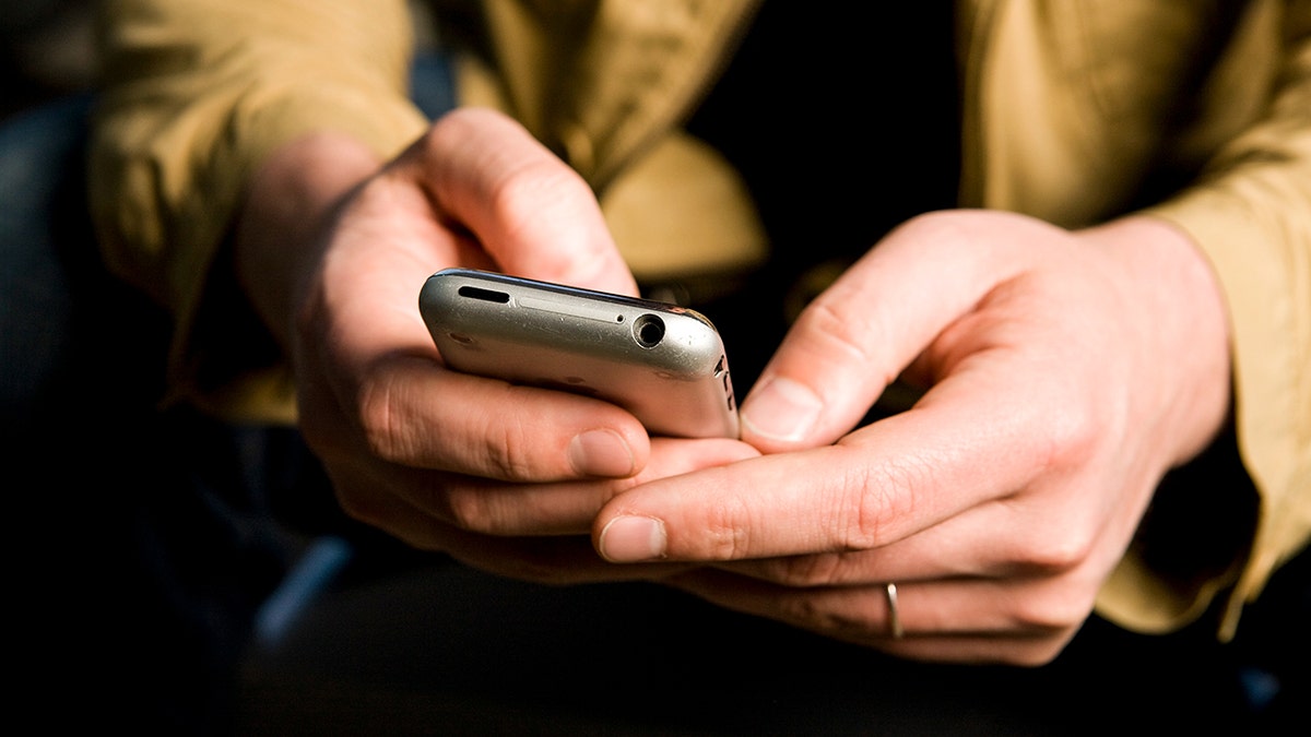 Man typing into his smartphone.