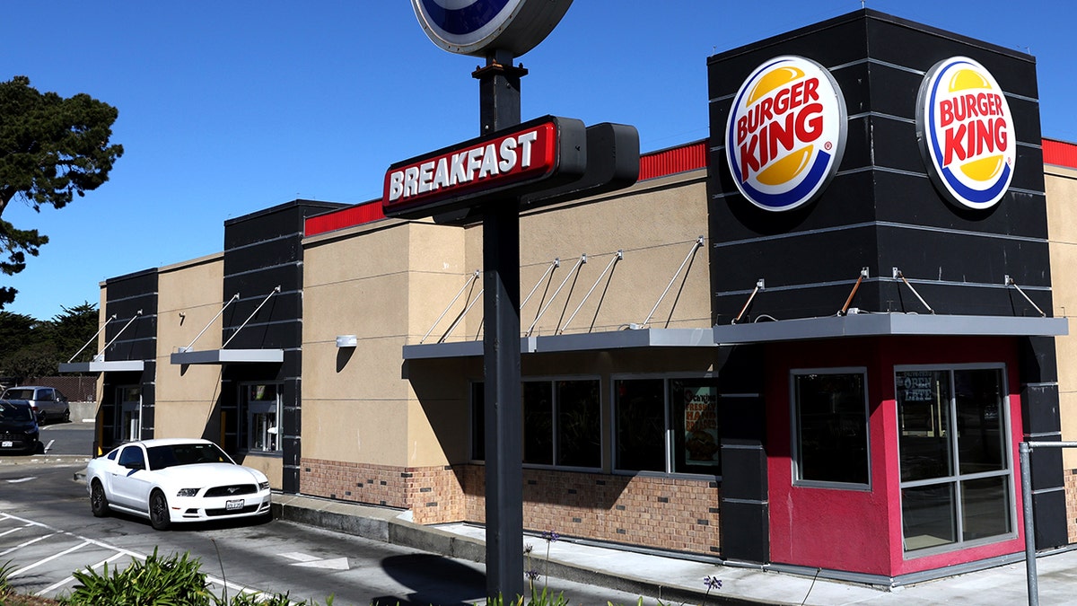 A white car sits at the window of a Burger King drive