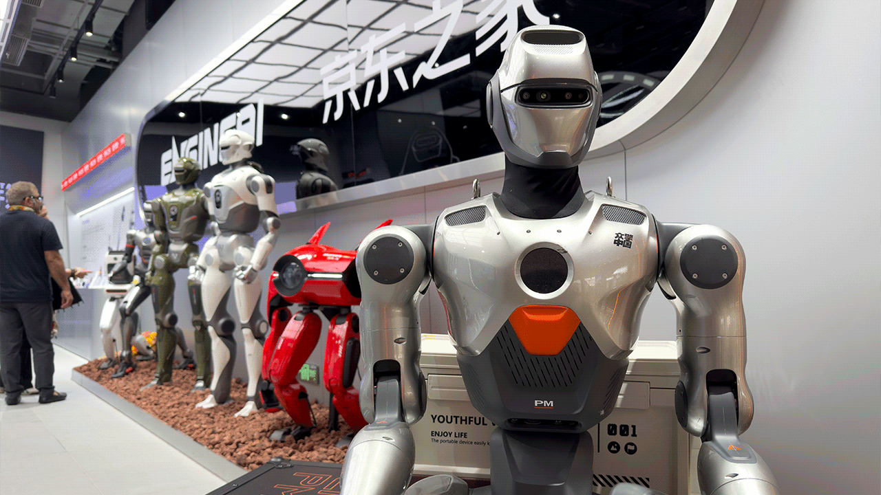 An EngineAI PM01 humanoid robot stands in front of a line of other robots.